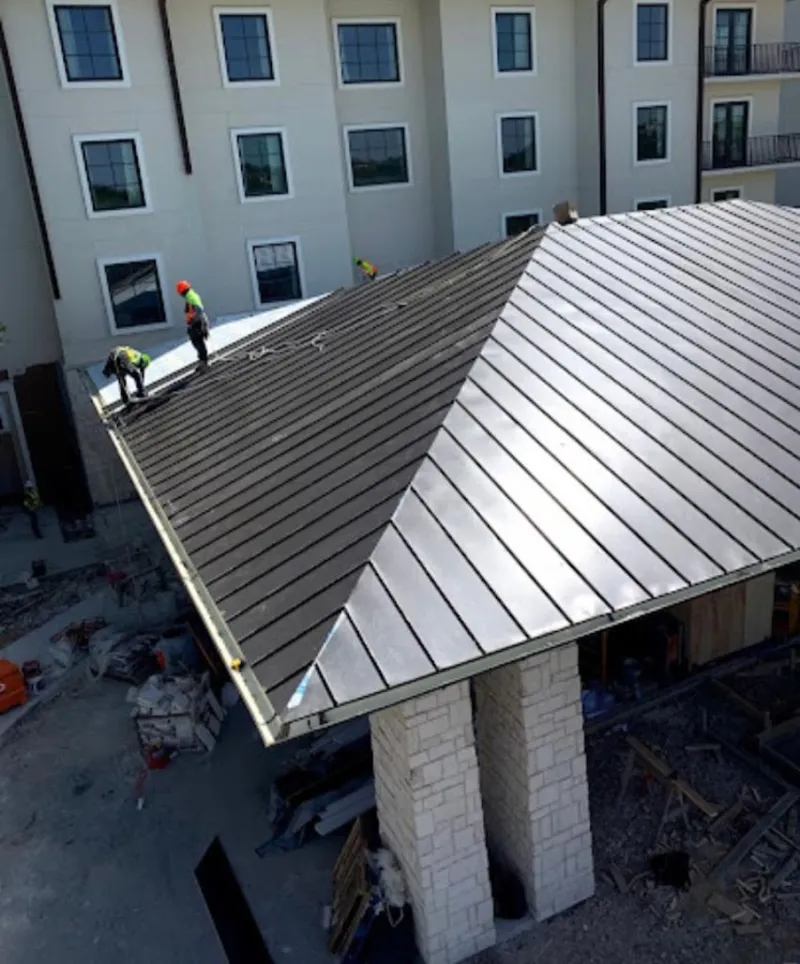 Crew installing standing seam metal roof panels on a commercial project in Calhoun